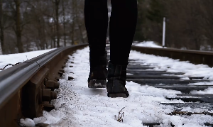 女子在雪后火车道走路情感特写视频素材